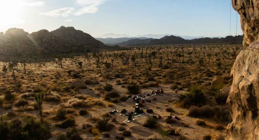 From above a group of people appear small amid a desert landscape. 